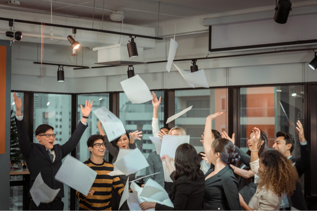 An image of a group of sales reps celebrating being able to easily see their commissions by throwing their papers in the air.