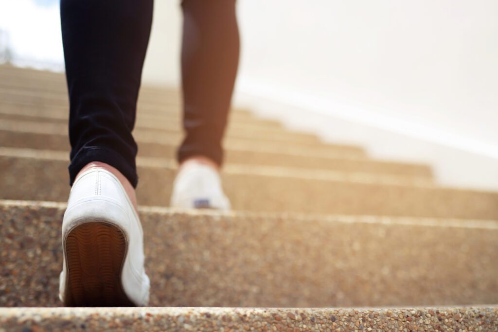 A closeup image of a woman's feet as she starts to climb the stairs of commission management.