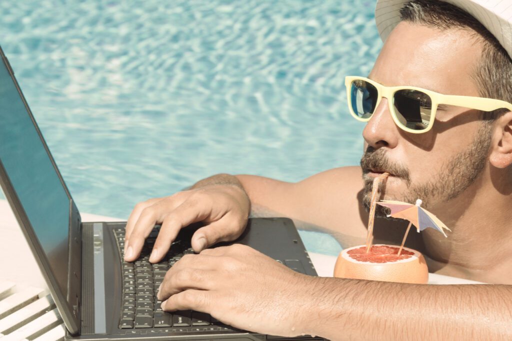 An image of a man lounging in a pool sipping on a grapefruit cocktail and using his computer to easily calculate commissions using commission software.