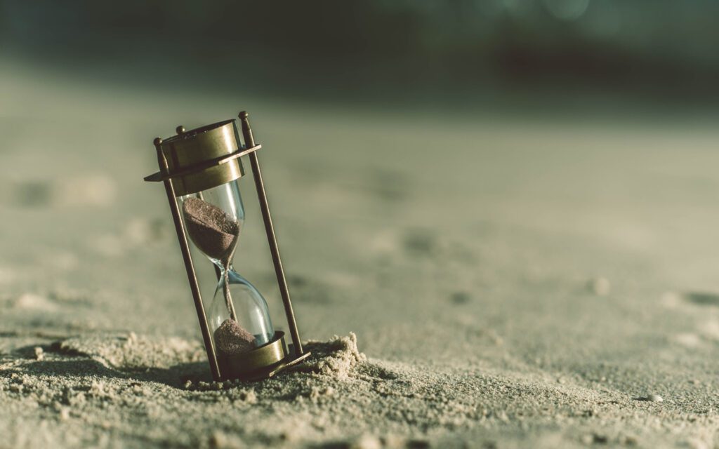 An image of an hourglass sitting on sand representing the time one can save by commission automation.