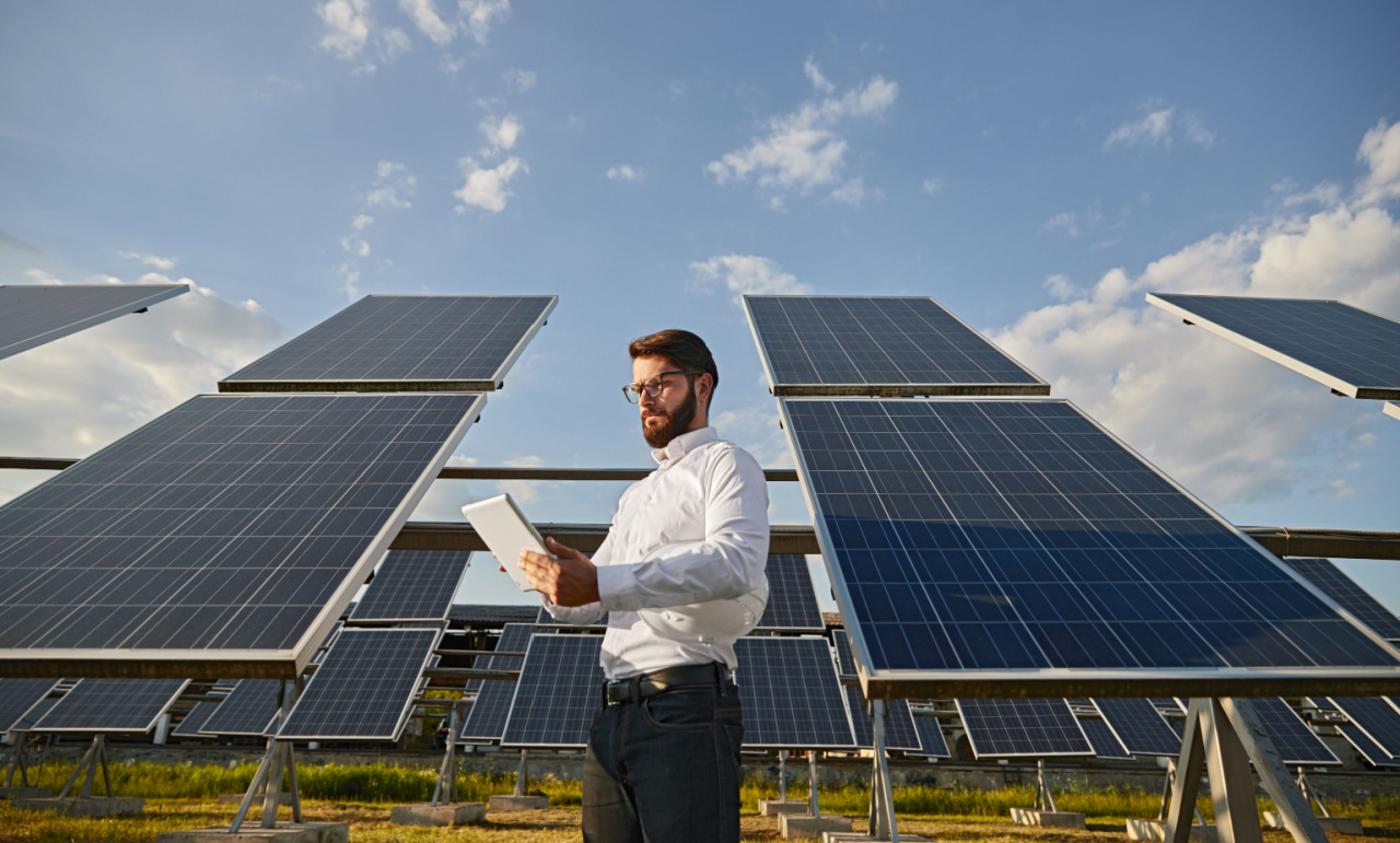 Solar sales rep standing in front of a rows of solar panels calculating his commissions