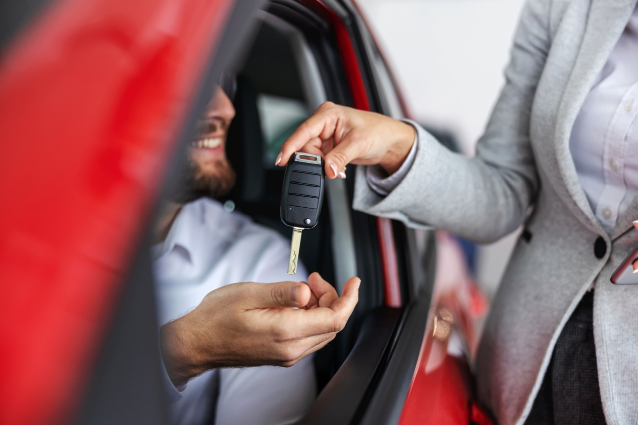Car sales rep delivers keys to customer in vehicle.